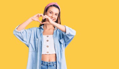 Genç, güzel bir kız, gündelik tişört giyiyor ve Diadem gülüyor. Aşkla gülümsüyor. Elleriyle kalp sembolü ve şekli gösteriyor. romantik kavram. 