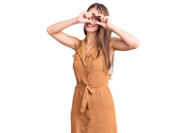 Genç, güzel, sarışın bir kadın. Günlük kıyafetler ve gözlük takıyor. Kalp şeklinde. El ve parmaklarıyla gülümsüyor. 