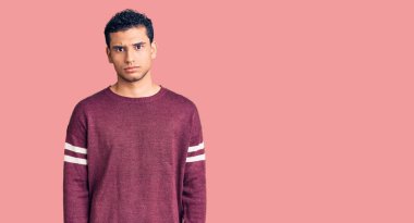 Hispanik yakışıklı genç adam gündelik kıyafetler giyiyor şüpheci ve gergin, sorun yüzünden surat asıyor. negatif kişi. 