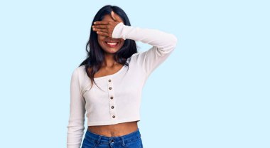 Gündelik kıyafetler giyen genç Hintli bir kız. Gülümseyen ve gülen elleri yüzlü. Şaşırtmak için gözleri örtüyor. kör kavram. 