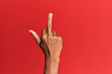 Hand of hispanic man over red isolated background showing provocative and rude gesture doing fuck you symbol with middle finger 