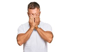 Yakışıklı, beyaz tişört giyen, yorgunluk ve baş ağrısı için gözlerini ovuşturan, uykulu ve yorgun ifadeli kaslı bir adam. görme sorunu 