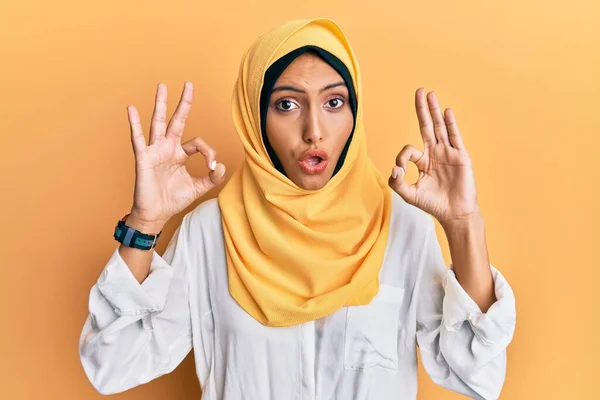 伝統的なイスラムのヒジャーブスカーフを身に着けている若いブルネットのアラブ女性は驚いて 指でOk承認シンボルをやってショックを受けた クレイジーな表現 — ストック写真