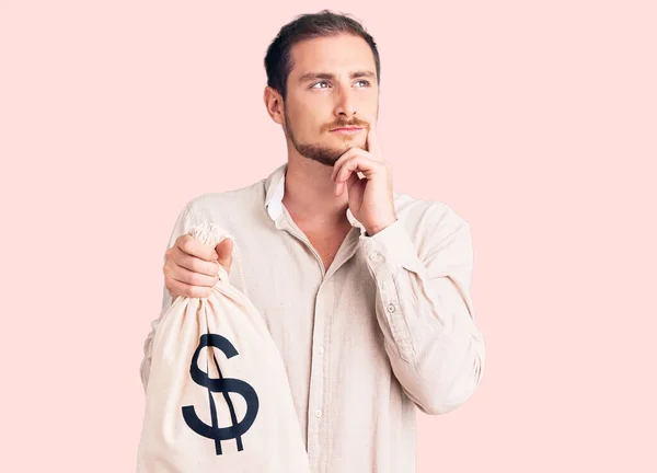 Jovem Caucasiano Bonito Segurando Saco Dinheiro Com Símbolo Dólar Rosto — Fotografia de Stock
