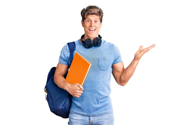 Joven Hombre Guapo Con Mochila Estudiante Auriculares Sosteniendo Libro Celebrando —  Fotos de Stock