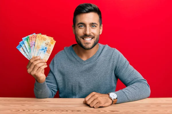 スイスのフラン紙幣を持っているハンサムなヒスパニック系の男は 肯定的で幸せな立っており 歯を示す自信を持って笑顔で笑っています — ストック写真