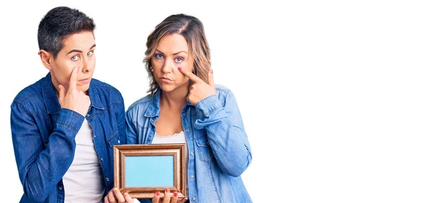 Couple Women Holding Empty Frame Pointing Eye Watching You Gesture — Stock Photo, Image