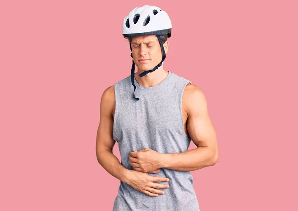 若いハンサムな男が胃の上に手で自転車のヘルメットを身に着けているので 消化不良 痛みを伴う病気が具合が悪い キャッシュ コンセプト — ストック写真