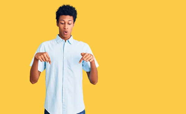 身穿休闲装的年轻的非洲裔美国人 手指朝下 露出广告 惊讶的面孔和张开的嘴 — 图库照片