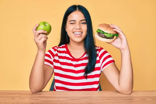 Fiatal Ázsiai Lány Összehasonlítva Burger Egészséges Alma Kacsintás Néz Kamera — Stock Fotó