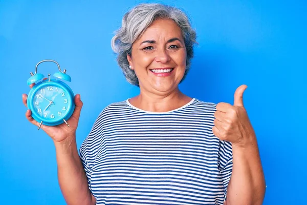 Ältere Hispanische Frau Hält Wecker Lächelnd Glücklich Und Positiv Daumen — Stockfoto