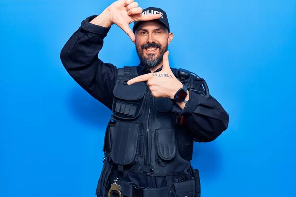 Young handsome man wearing police uniform smiling making frame with hands and fingers with happy face. creativity and photography concept.