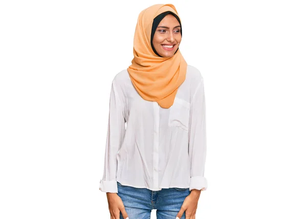 伝統的なイスラムヒジャーブスカーフを身に着けている若いブルネットの女性は顔に笑顔で横に離れて見て 自然な表情 自信を持って — ストック写真