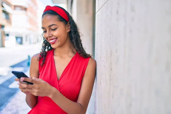 Joven Afroamericana Chica Sonriendo Feliz Usando Teléfono Inteligente Apoyado Pared —  Fotos de Stock