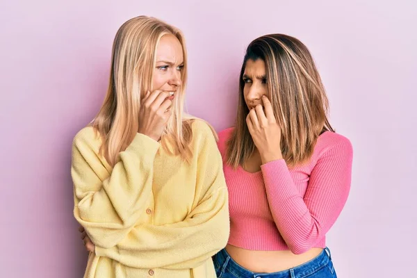 两个朋友站在粉红的背景上 双手放在咬指甲的嘴上 看起来很紧张 很紧张 焦虑问题 — 图库照片