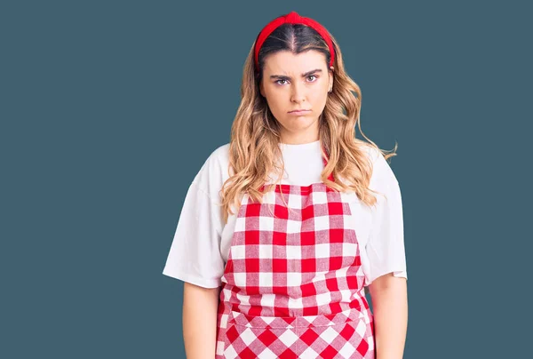 Young caucasian woman wearing apron skeptic and nervous, frowning upset because of problem. negative person.