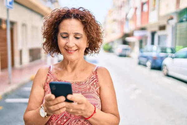 Μέση Ηλικία Γυναίκα Χαμογελώντας Ευτυχισμένη Χρησιμοποιώντας Smartphone Περπάτημα Στο Δρόμο — Φωτογραφία Αρχείου