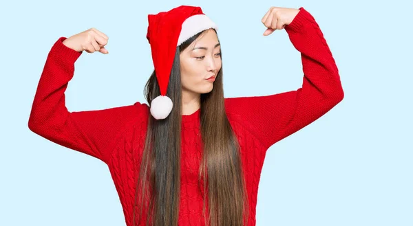 Mulher Chinesa Jovem Usando Chapéu Natal Mostrando Músculos Braços Sorrindo — Fotografia de Stock