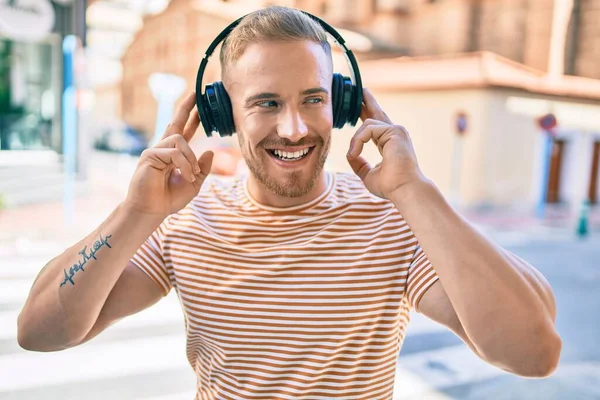 若いアイルランド人の男は 街の通りでヘッドフォンを使用して音楽を聞いて幸せな笑顔 — ストック写真