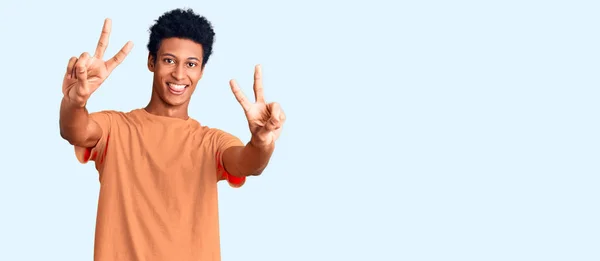 年轻的非洲裔美国人穿着休闲装 用舌头笑着 伸出双手的手指做胜利的标志 第二点 — 图库照片