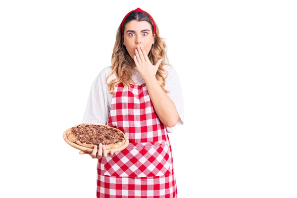 Νεαρή Καυκάσια Γυναίκα Φορώντας Ποδιά Κρατώντας Πίτσα Που Καλύπτει Στόμα — Φωτογραφία Αρχείου