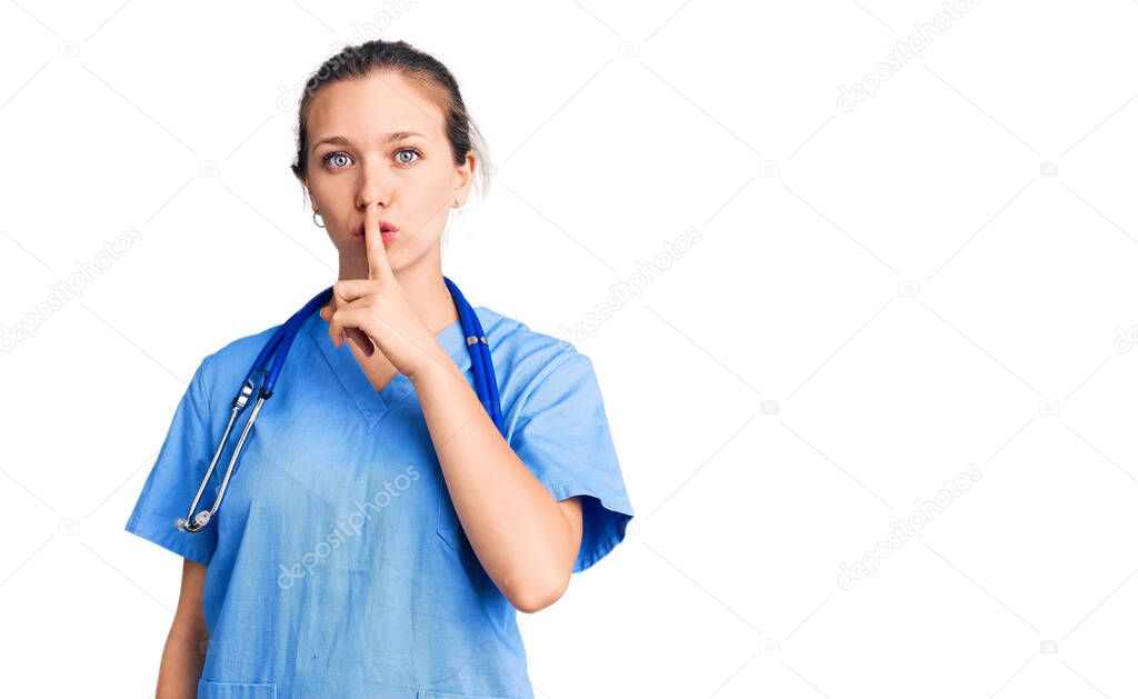 Young beautiful blonde woman wearing doctor uniform and stethoscope asking to be quiet with finger on lips. silence and secret concept. 