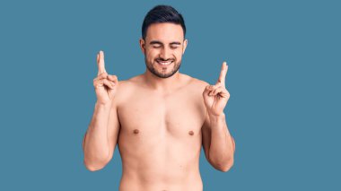 Mayo giyen genç yakışıklı adam umut ve gözlerin kapalı gülümseyerek işaret ediyor. Şans ve batıl inançlar. 