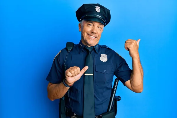 Handsome middle age mature man wearing police uniform pointing to the back behind with hand and thumbs up, smiling confident