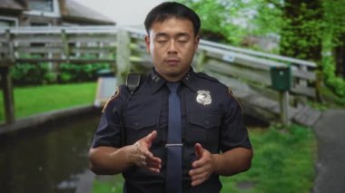 Üniformalı Çinli adam açık avuçlar ve kapalı gözler gösteriyor. Elinde radyo var. Güvenlik güvencesi sakin..