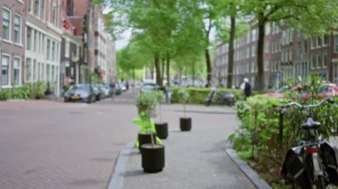 Açık şehir ortamında arabaları, bisikletleri ve yeşillikleri gösteren Avrupa 'nın bulanık sokak manzarası hareketli bir toplum atmosferinin altını çiziyor.