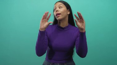 Stüdyoda nane yeşili arka planda konuştuğu için mor jest yapan genç Latin kadın..