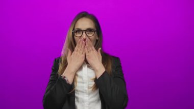 Mor bir stüdyoda gözlük takan ve elleri ağzı kapalı bir ceket giyen genç bir kadın. Sürpriz..