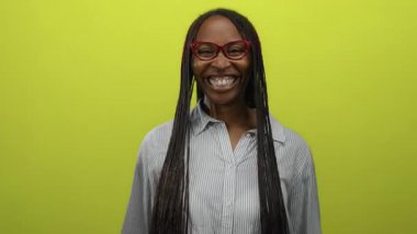 Gözlüklü bir kadın canlı sarı bir duvara gülümsüyor mutluluk ve güven saçıyor..