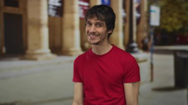 Adam açık havada gülümserken tarihi kampüs sütunlarına ön cephe inşa etmeye parmak basıyor; güven başarısı.