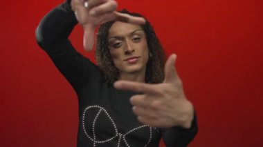 İspanyol transseksüel kadın, elleri kırmızı stüdyo duvarının önünde dik dik bakan, odaklan..