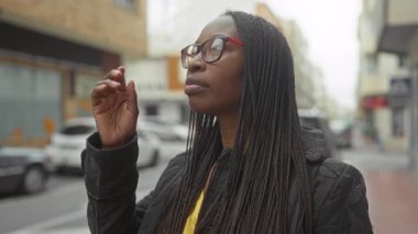 Örgü ören kadın şehir sokaklarında gözlük takıyor. Meşgul şehir hayatının ortasında afro amerikan güzelliği ve modası sergiliyor..