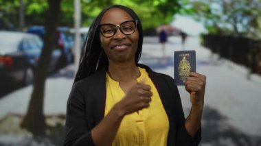 Kentsel alanda elinde Kanada pasaportuyla gülümseyen bir kadın. Gözlüklü, sarı gömlekli, şehir arka planında bulanık bir ifade ve mutlu bir jest sergiliyor..