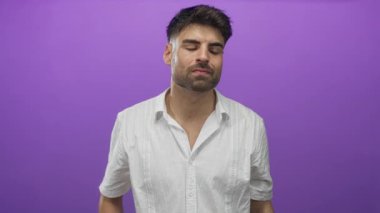 Beyaz gömlekli ve sakallı İspanyol bir adam stüdyo ortamında parmağıyla şakağına işaret ediyor..