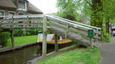 Hollanda, giethoorn 'daki bulanık kanal manzarası, ahşap köprünün altında çözünmüş tekne, yemyeşil ve geleneksel evlerle çevrili..