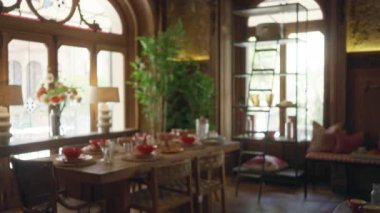 İçeriye ahşap dekorla kurulmuş zarif bir yemek odası manzarası, büyük pencereler ve rafın yanında bir yemek masası, sandalyeler ve canlı çiçekler..