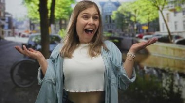 Sarışın, kot gömlek ve açık palmiyeli açık bluz giyen genç bir kadın, saf şaşkınlık..