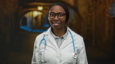 Şehir ortamında, steteskop, gözlük ve sakin tavır takınarak güvenle gülümseyen kadın profesyonel, tıbbi varlığın altını çiziyor..