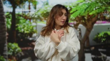 Canlı yeşilliklerle dolu yemyeşil bir parkta korkuyu ifade eden, beyaz kıyafetler giyen, gündüz vakti açık havada duygusal olarak anımsatıcı bir anı doğal bir arka planla yakalayan bir kadın..