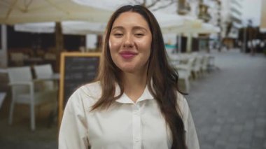 Beyaz gömlekli kadın, açık hava lokantasında doğal ışık altında dilini dışarı çıkartıyor..