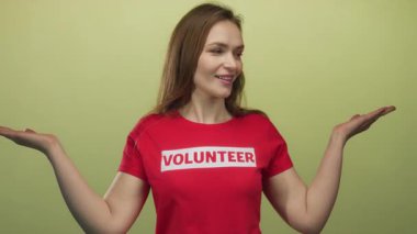 Gönüllü kadın stüdyoda açık avuç içlerini kırmızı gömlekli yumuşak açık yeşil duvara karşı tutuyor..