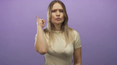 Mor arka plana karşı ciddi bir ifadeyle işaret eden bir kadın. Otorite ve odaklanma, izole edilmiş, el hareketi, genç ve kendinden emin.