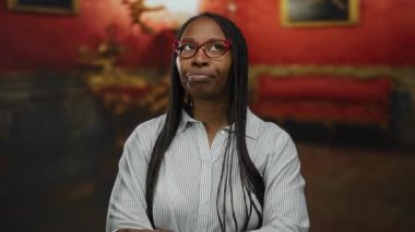 Gözlüklü ve kıvırcık saçlı bir kadın renkli bir müzede umut verici görünüyor..