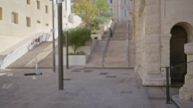 Bulanık sahne, Marsilya 'daki kentsel caddeyi mimari merdivenlerle ve yumuşak gün ışığında Bokeh efektiyle tasvir ediyor..