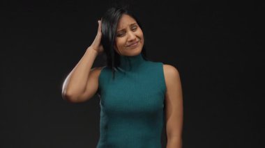 Açık havada Latin bir kadın, el ele tutuşup gündüz vakti şehir sokaklarında düşünceli bir ifade sergiliyor..