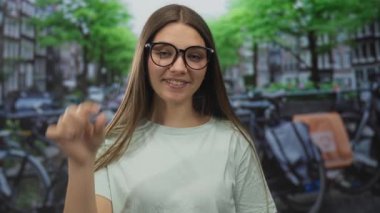 Genç kız, yoğun bir caddede park halindeki bisikletli bir kanalın yanında hafif bir gülümsemeyle gözlük ayarlıyor..